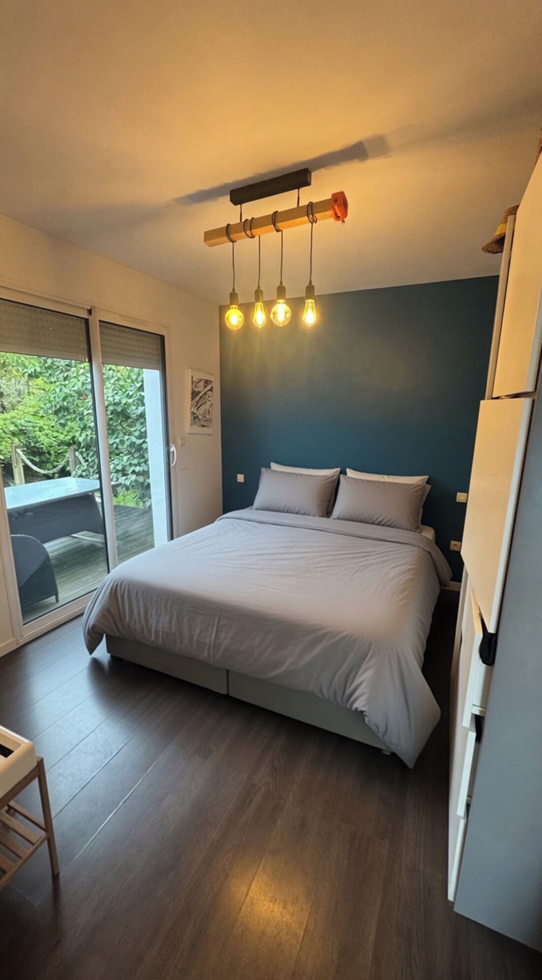 A bedroom with a bed, a ceiling light fixture, and a sliding glass door leading to an outdoor area.