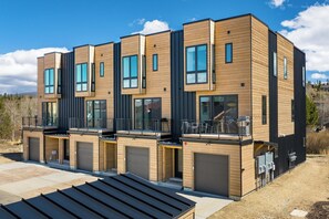 Ein modernes, mehrgeschossiges Wohngebäude mit großen Fenstern, Balkonen und Garagentoren.