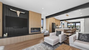 Ein modernes Wohnzimmer mit Kamin, weißen Sofas und einem großen Fernseher.