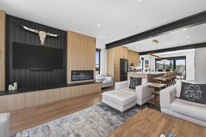 Ein modernes Wohnzimmer mit Kamin, weißen Sofas und einem großen Fernseher.