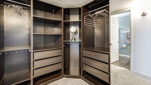 Ein begehbarer Kleiderschrank mit offenen Regalen, einem Spiegel und einer Kleiderstange.