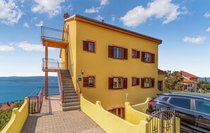 Ein gelbes Gebäude mit Treppe, Balkon und Meerblick.