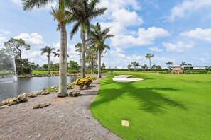 Ein Golfplatz mit Teich, Palmen und einem gepflegten Grün.