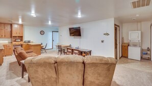 Ein Wohnzimmer mit braunem Ledersofa, Holzschränken, einem Essbereich und einer Küche mit Kühlschrank und Mikrowelle.