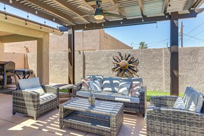 Eine Terrasss mit Korbmöbeln, Deckenventilator und dekorativer Sonnenstrahl-Wandgestaltung.
