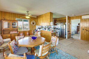 Una cocina con paneles de madera, una mesa de comedor, sillas y un refrigerador.