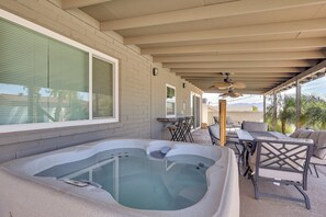 Eine überdachte Terrasse im Freien mit Whirlpool, Sitzgruppe und Tisch.