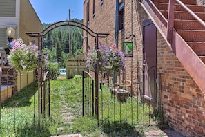 A rustic building with a brick facade, a metal gate, and a staircase leading to a door.