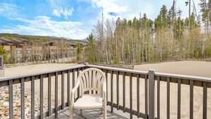 A deck with a chair, a wooden railing, and a view of buildings and trees. - Summer Fun! Winter Park Condo w/ Pool, Hot Tub (Winter Park)