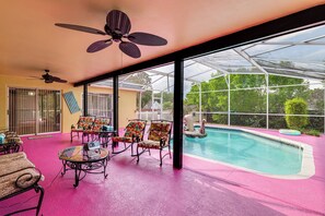 Ein Poolbereich mit Liegestühlen und Deckenventilator.