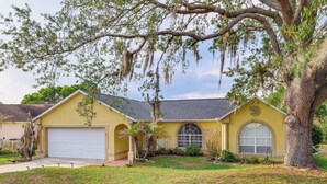 A single-story house with a garage, a large tree with Spanish moss, and a well-maintained lawn. - Themed Interior, Poolside Fun! Villa Near Disney (Davenport)