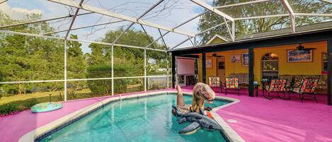 Una piscina con juguetes inflables, un porche cubierto y mobiliario de exterior.