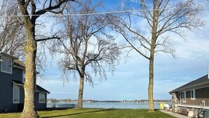 Ett bostadsområde med två hus, en gräsyta och en vattenyta i bakgrunden.