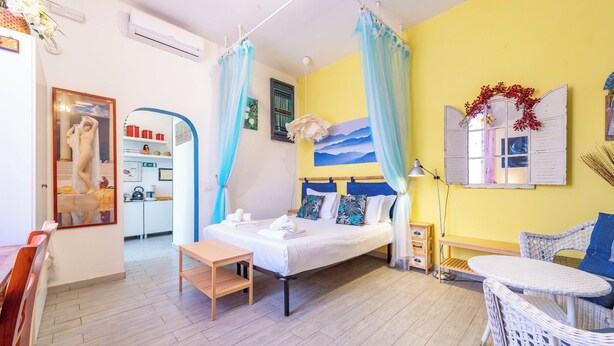 Hotellihuone, jossa on sänky, pieni pöytä, tuoli, työpöytä ja peili.