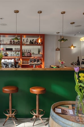 Una zona de bar con taburetes, una barra y estantes llenos de botellas.
