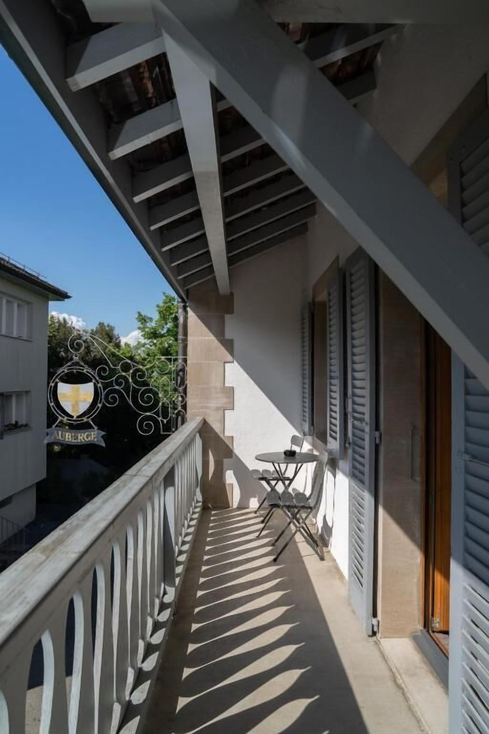 A balcony with a railing, a table with chairs, and a door leading to an interior space.