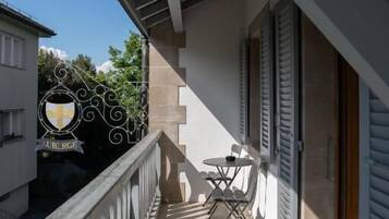 A balcony with a railing, a table with chairs, and a door leading to an interior space.