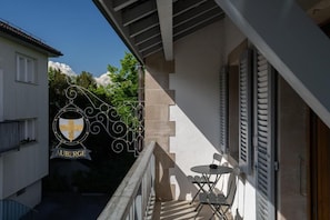 A balcony with a table and chairs, a building with a sign reading 'AUBERGE,' and a clear sky. - Auberge De Confignon (Confignon)