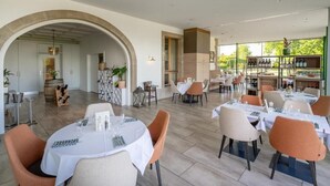 A restaurant with round tables, orange chairs, and a wine rack visible in the background.