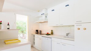 Una cocina moderna con armarios blancos, lavavajillas, cafetera y ventana con vista a zonas verdes.