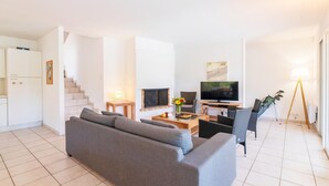 Una sala de estar moderna con sofá, televisión y comedor.