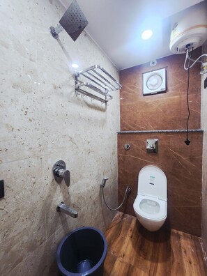 A bathroom with a toilet, shower, and a bucket. - Oly Hotel Sky Inn (New Delhi)