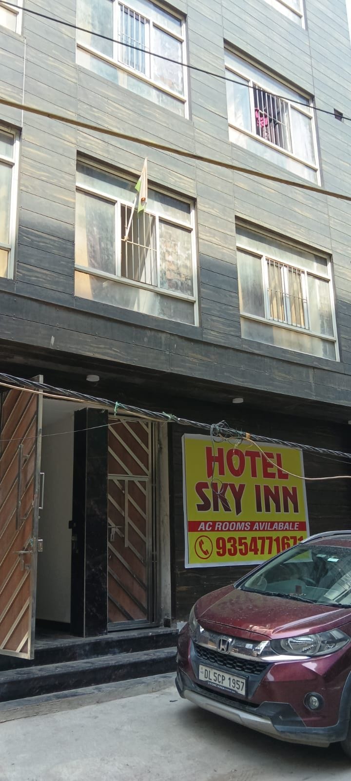 A multi-story building with a sign for 'Hotel Sky Inn' advertising AC rooms.