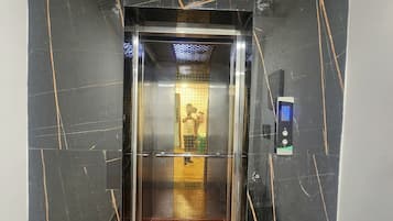 An elevator with a black marble wall and a metal door.