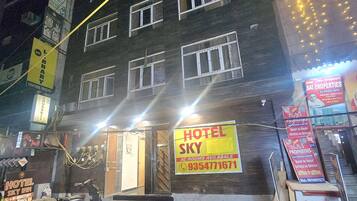 Un immeuble à plusieurs étages, sur lequel on peut voir une grande enseigne jaune indiquant « Hôtel Sky » et faisant la publicité de chambres climatisées.