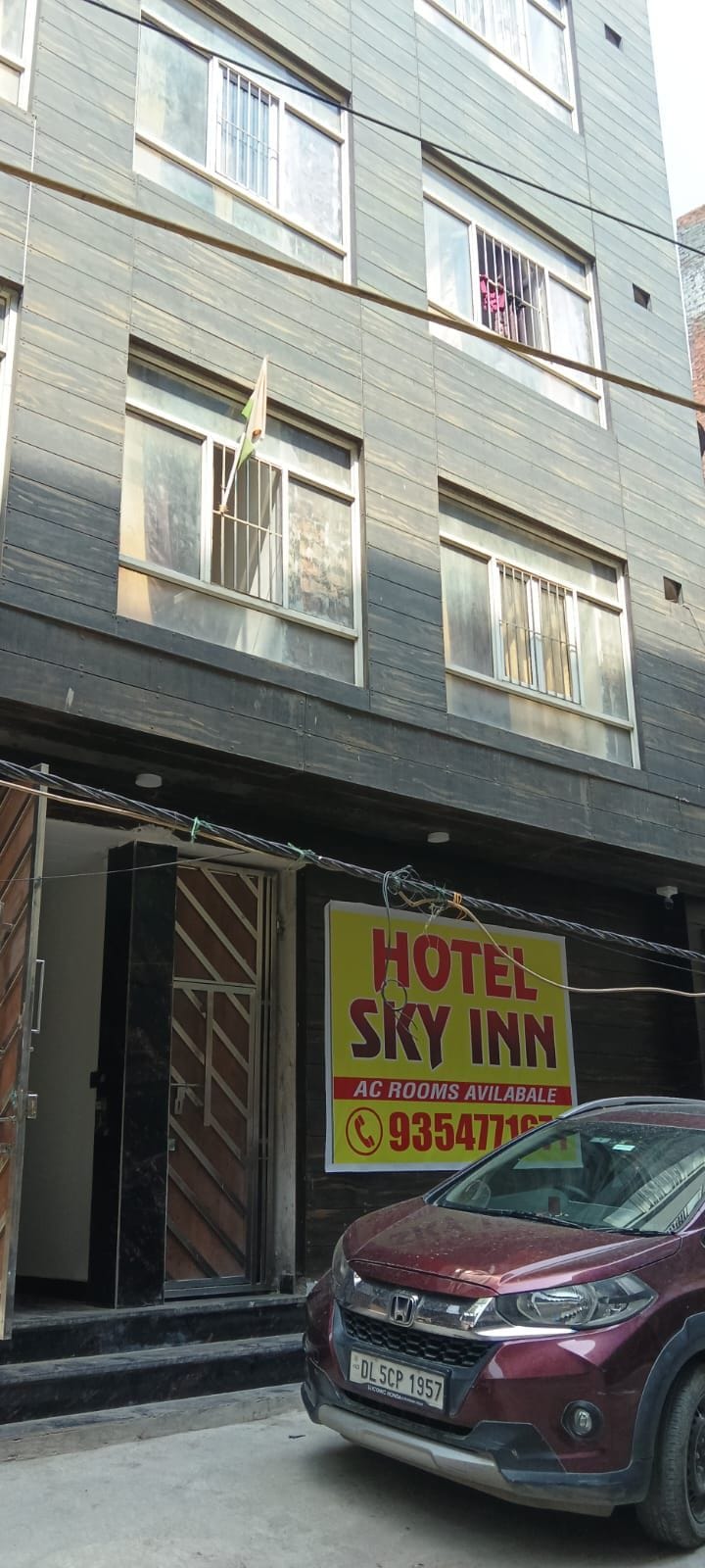 A hotel named 'Hotel Sky Inn' with a signboard advertising AC rooms available for rent.