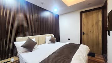 Een hotelkamer met een bed, nachtkastje en een houten deur.