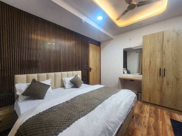 Una habitación de hotel con cama, paneles de madera, ventilador de techo y armario.