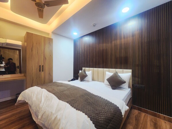 A modern bedroom with a bed, wooden wardrobe, and a mirror. - Oly Hotel Sky Inn (New Delhi)
