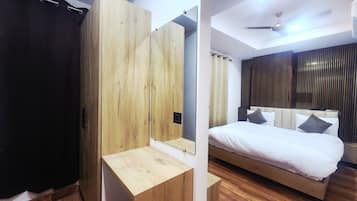 Een slaapkamer met een bed, een houten garderobe, een spiegel en een plafondventilator.