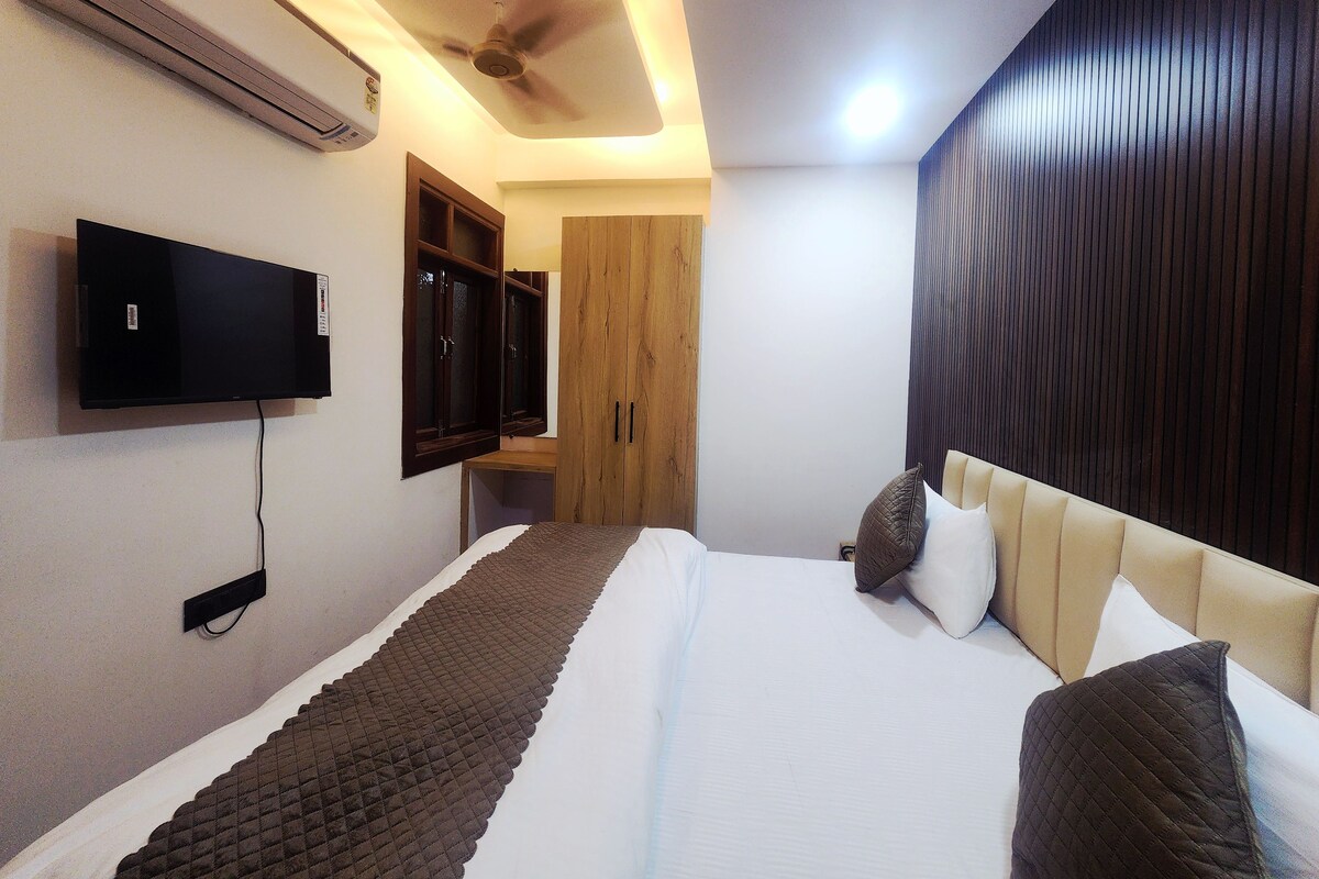 A bedroom with a bed, a television mounted on the wall, and a ceiling fan.