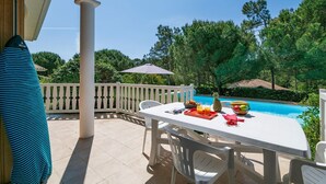 Eine Terrasse mit Frühstückstisch, einem Pool und einem weißen Zaun.