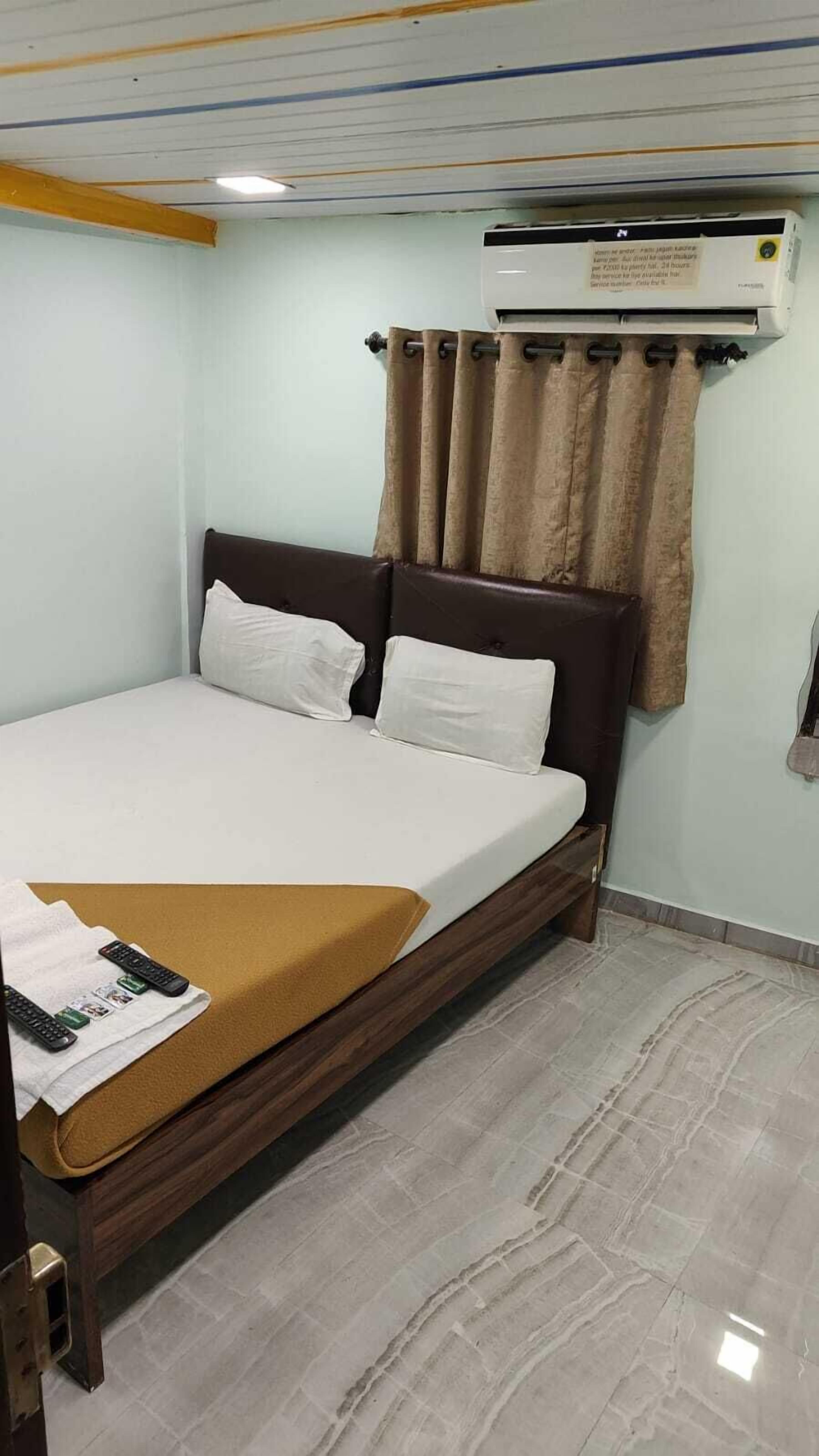 Una habitación de hotel con cama, televisor de pantalla plana, calefacción y cortina.
