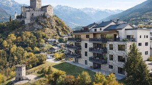 Un château perché sur une colline, avec un bâtiment moderne en premier plan.