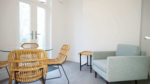 A room with a glass table, two wicker chairs, a small wooden table, and a light-colored sofa. - Bright 1BDR Flat between Forest Hill East Dulwich (Greater London)
