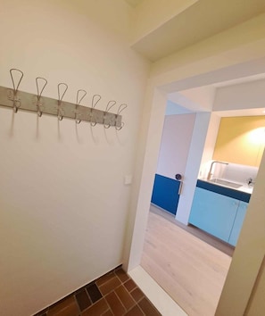 Ein Flur, der zu einer modernen Küche führt, mit Garderobe und einer sichtbaren Tür.