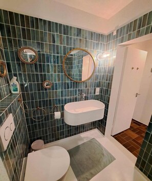 Ein Badezimmer mit einem weißen Waschbecken, zwei Spiegeln und einer Toilette.