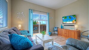 Ein Wohnzimmer mit einer Couch, einem Couchtisch und einem an der Wand befestigten Fernseher.