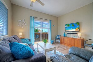 Ein Wohnzimmer mit einer Couch, einem Couchtisch und einem an der Wand befestigten Fernseher.