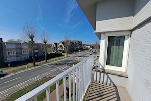 Un balcón con vista a una calle residencial, casas y un cielo despejado.