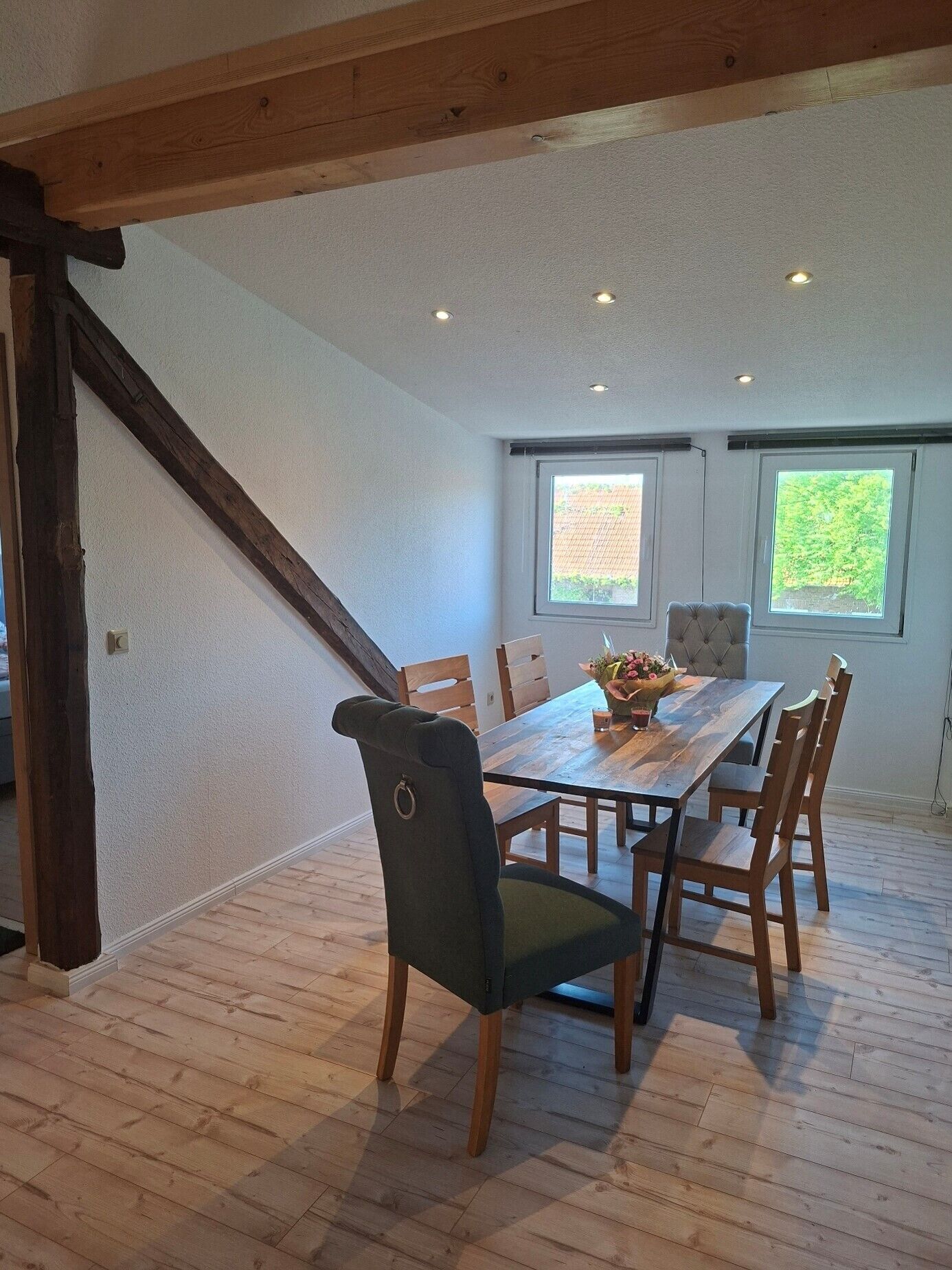 A dining area with a wooden table, chairs, and a window with a view.