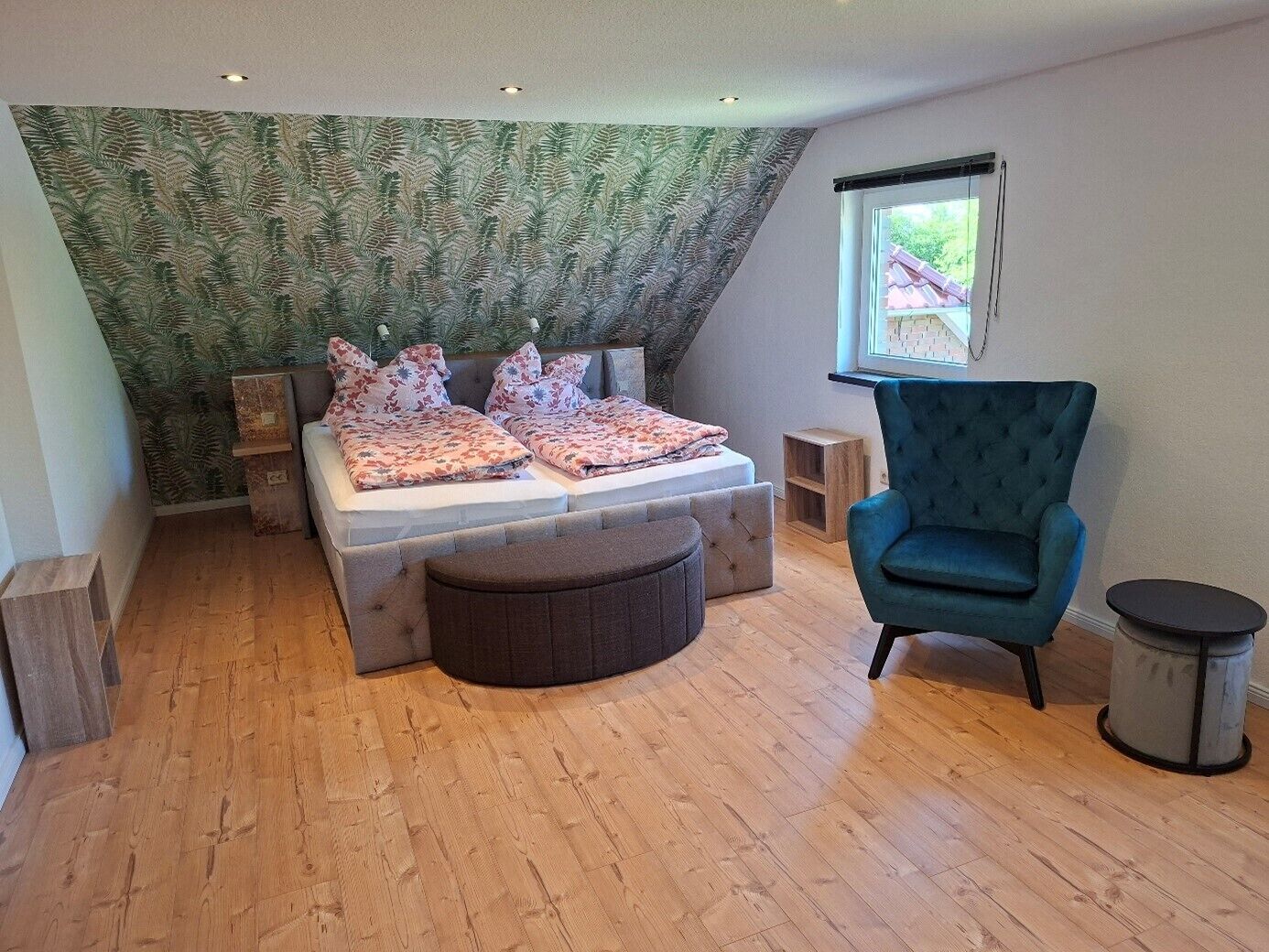 A bedroom with a bed, a chair, a window, and a patterned wall.