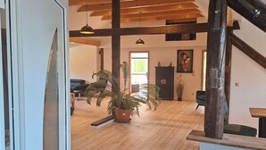 A spacious room with wooden flooring, a staircase, and a large potted plant.