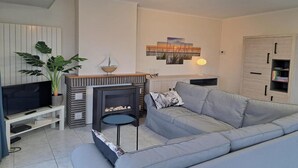 Ein Wohnzimmer mit einer Couch, Fernseher, Kamin und einer Pflanze.