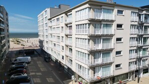 Ein mehrstöckiges Hotel mit Balkonen, einem Parkplatz und Blick auf den Strand.