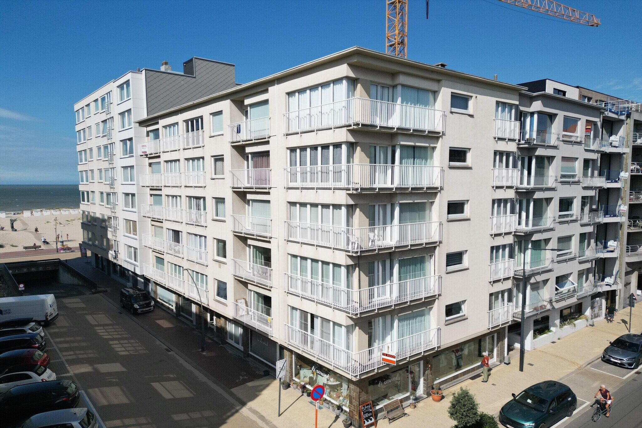 A multi-story hotel with balconies, a beach view, and a parking area.